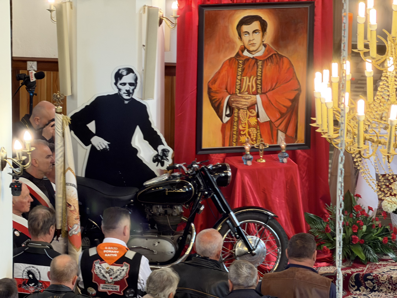  Obraz bł. ks. Jerzego Popiełuszki, makieta jego postaci i motocykl ustawione w kościele w Grannem podczas uroczystości